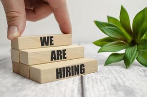 we are hiring words on wooden block and businessman hand photo