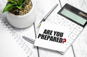 Text Are You Prepared Question on paper card and calculator on wooden background photo