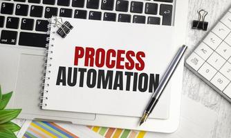 texto de automatización de procesos en bloc de notas y portátil, calculadora y bolígrafo foto