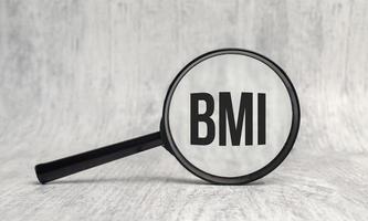 The word BMI is written on magnifying glass and white background photo
