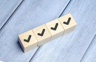 Checklist and check mark concept. Check mark on wooden blocks on light blue background photo