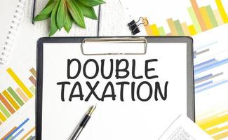 Double Taxation. text on notepad on wood table photo