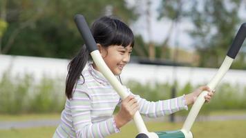 Asian little girl enjoy to playing on outdoor exercise equipment with smile, at playground video