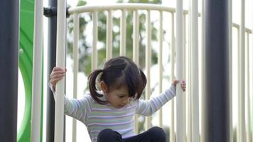 Handheld shot, Portrait Asian little girl play alone on slider in playground video