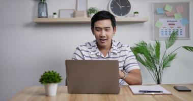 portrait d'un homme d'affaires asiatique heureux avec un ordinateur portable travaillant au bureau à domicile et recevant de bonnes nouvelles par e-mail. joyeux gagnant masculin profite du succès au bureau à domicile.