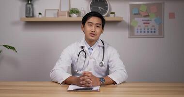 el retrato de un joven médico asiático con estetoscopio hace una videollamada en línea consulta al paciente y mira la cámara. asistente médico terapeuta videoconferencia. concepto de pandemia de telemedicina. video