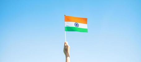 hand holding India flag on blue sky background. Holiday of India republic Day, happy Independence day and Gandhi Jayanti concepts photo