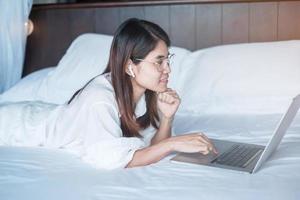 Happy woman using laptop for work, female meeting  online by computer notebook on bed. technology, network, work from home, lifestyle and digital communication concept photo