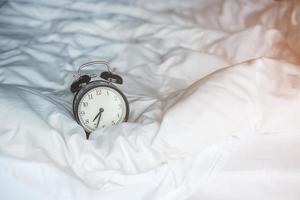 Vintage alarm clock on bed and copy space for text. Wake up, sleeping, daily routine, morning, workout and Work life balance concept photo