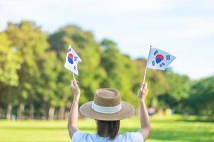 Woman hand holding Korea flag on nature background. National Foundation, Gaecheonjeol, public Nation holiday, National Liberation Day of Korea and happy celebration concepts photo