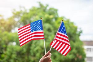 hand holding United States of America flag on green background. USA holiday of Veterans, Memorial, Independence and Labor Day concept