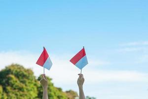 mano que sostiene la bandera de indonesia sobre fondo de cielo azul. día de la independencia de indonesia, día festivo nacional y conceptos de celebración feliz foto