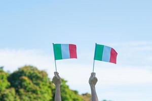 mano sosteniendo la bandera de italia en el fondo de la naturaleza. día nacional, día de la república, festa della repubblica y conceptos de celebración feliz foto