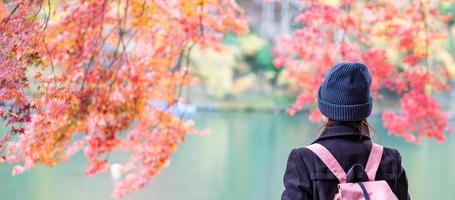 Happy woman tourist looking colorful leaves and Katsura river in Arashiyama, young Asian traveler visit in Kyoto and enjoy travel in Japan. Fall Autumn season, Vacation,holiday and Sightseeing concept