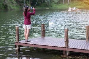 Happy traveler woman taking photo Nature view by smartphone , solo tourist in sweater traveling at Pang Oung, Mae Hong Son, Thailand. travel, trip and vacation concept