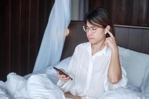 Happy woman using smart phone for video call, female meeting  online by mobile phone on bed. technology, network, work frome home, lifestyle and digital communication concept photo