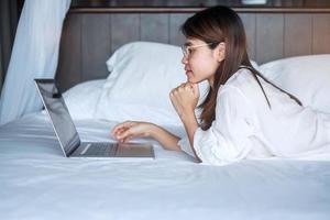 Happy woman using laptop for work, female meeting  online by computer notebook on bed. technology, network, work from home, lifestyle and digital communication concept photo