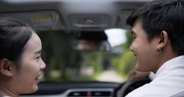 ritratto di coppia asiatica parlando in auto, sorridente e guardando la fotocamera. concetto di viaggio e stile di vita. video