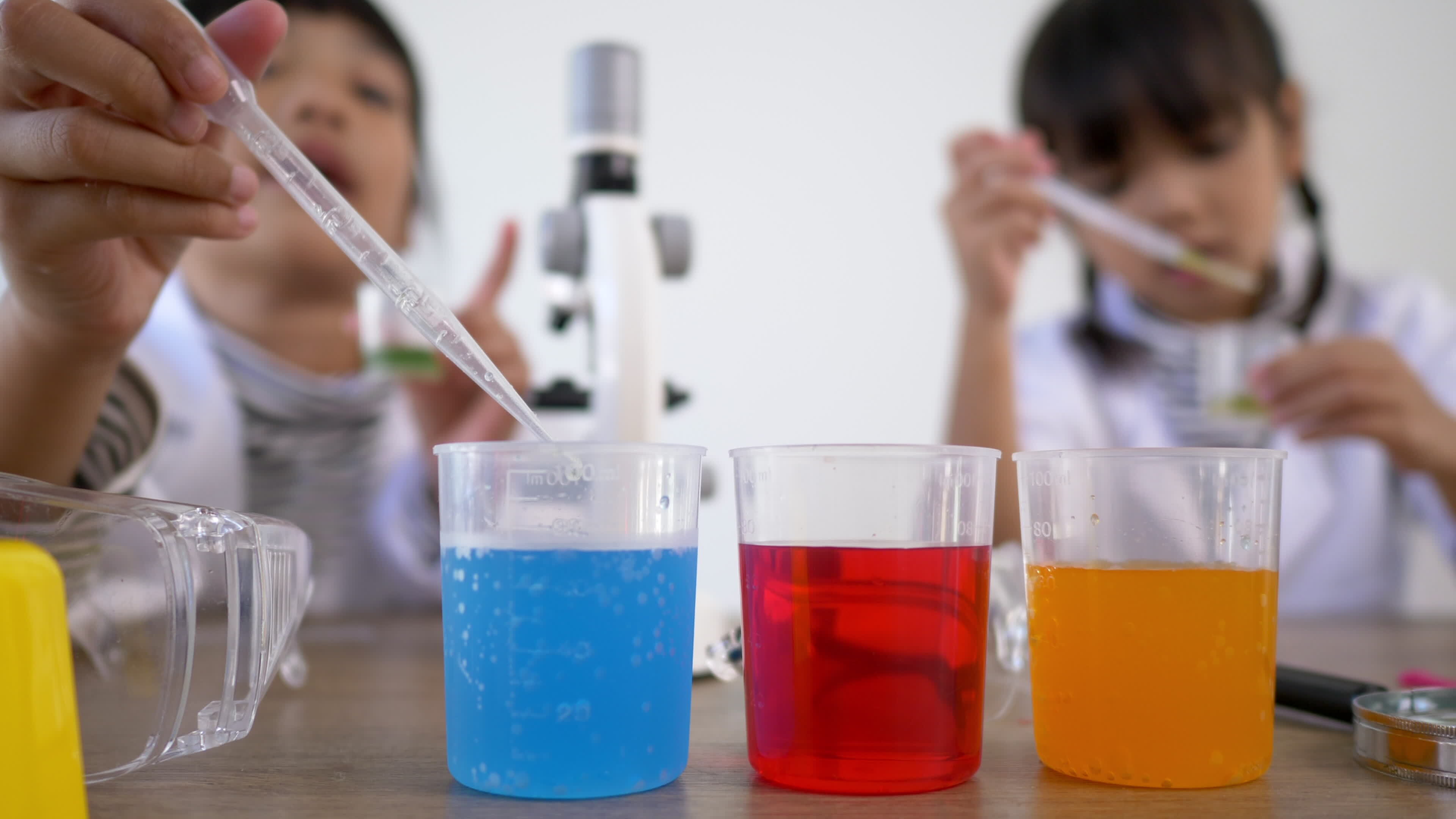 Selective focus at three colors liquids in beakers, blur Asian little