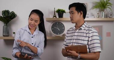 Portrait of Asian businesswoman presenting project to businessman in office. Female holding laptop and male making note. video