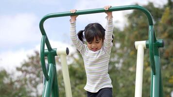 Asian little girl enjoy to playing on outdoor exercise equipment with smile, at playground video