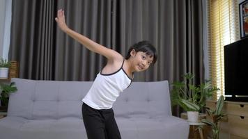 linda garota asiática de pé em uma perna e mantendo o equilíbrio no tapete na sala de estar em pose de meditação em casa video