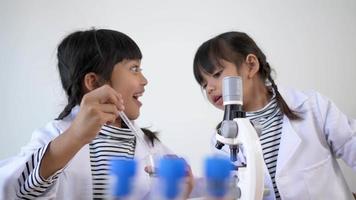 Two Asian siblings wearing coat are using the device for experimenting with liquids. They talking while studying science chemistry with fun