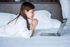 Happy woman using laptop for work, female meeting  online by computer notebook on bed. technology, network, work from home, lifestyle and digital communication concept photo