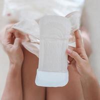 manos de mujer sosteniendo toallas sanitarias o servilletas de menstruación durante su uso. menses, femenino, período menstrual, período mensual y conceptos de higiene personal foto
