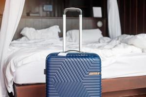 equipaje azul en la habitación de hotel moderna después de abrir la puerta. tiempo para viajar, servicio, viaje, viaje, vacaciones de verano y conceptos de vacaciones foto