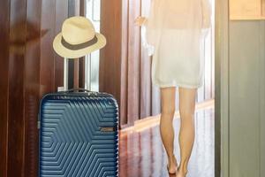 equipaje azul con sombrero en la habitación de hotel moderna después de abrir la puerta. tiempo para viajar, servicio, viaje, viaje, vacaciones de verano y conceptos de vacaciones foto