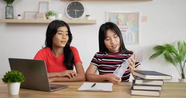 retrato de dos colegialas asiáticas que estudian en línea en una computadora portátil y una presentación con una computadora portátil en casa. concepto de aprendizaje y educación a distancia.