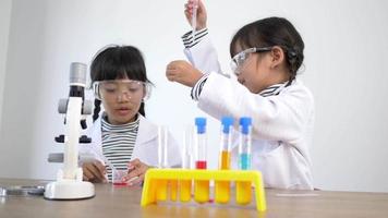 Two Asian siblings wearing coat and clear glasses are using the device for experimenting with liquids. while studying science chemistry video