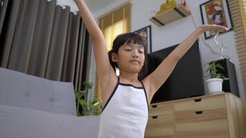 slow motion-bild, liten asiatisk flicka som sitter på mattan stängde ögat och placerade två händer på bröstet i meditationsasanaställning hemma video