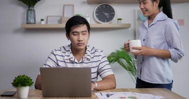 retrato de un hombre de negocios asiático serio que mira el monitor de la computadora en la oficina en casa. hombre de negocios enfocado leyendo el documento en la computadora portátil. hombre bebiendo café en la oficina oscura. video