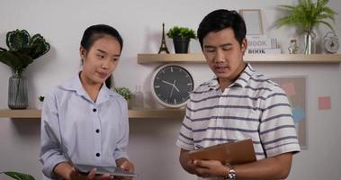 Portrait of Asian businesswoman presenting project to businessman in office. Female holding laptop and male making note. video