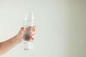 A hand is holding plastic bottle of water. photo