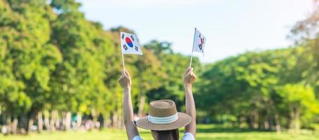 Woman hand holding Korea flag on nature background. National Foundation, Gaecheonjeol, public Nation holiday, National Liberation Day of Korea and happy celebration concepts photo