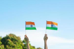 hand holding India flag on blue sky background. Holiday of India republic Day, happy Independence day and Gandhi Jayanti concepts photo