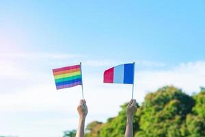 hands showing LGBTQ Rainbow and France flag on nature background. Support Lesbian, Gay, Bisexual, Transgender and Queer community and Pride month concept photo