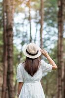 Happy traveler woman standing and looking Pine tree forest, solo tourist in white dress and hat traveling at Pang Oung, Mae Hong Son, Thailand. travel, trip and vacation concept