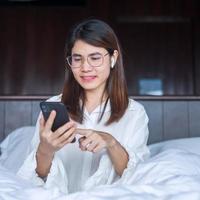 Happy woman using smart phone for video call, female meeting  online by mobile phone on bed. technology, network, work from home, lifestyle and digital communication concept photo