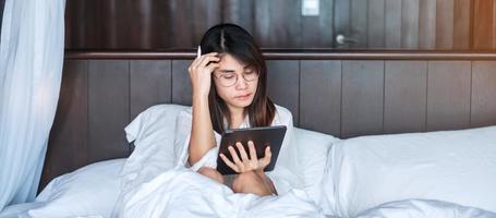 Happy woman using tablet for social media, young female watching movies on computer pad on bed at home. technology, network, online shopping, e commerce, lifestyle and digital communication concept photo