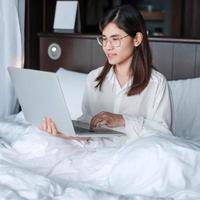 Happy woman using laptop for work, female meeting  online by computer notebook on bed. technology, network, work from home, lifestyle and digital communication concept photo