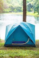 acampando bajo el bosque, carpa azul cerca del lago. concepto de viaje, viaje y vacaciones al aire libre foto