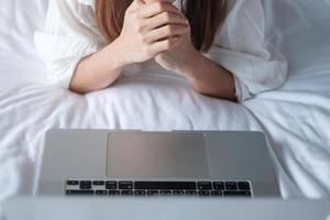 Happy woman using laptop for work, female meeting  online by computer notebook on bed. technology, network, work from home, lifestyle and digital communication concept photo