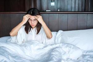 woman having migraine headaches during lying in bed at home. insomnia, sleepless, tired, suffering and stressed concepts photo