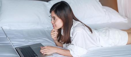 Happy woman using laptop for work, female meeting  online by computer notebook on bed. technology, network, work from home, lifestyle and digital communication concept photo