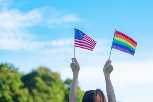 hands showing LGBTQ Rainbow and America flag on nature background. Support Lesbian, Gay, Bisexual, Transgender and Queer community and Pride month concept photo