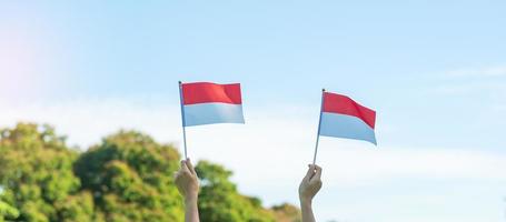 hand holding Indonesia flag on blue sky background. Indonesia independence day, National holiday Day and happy celebration concepts photo